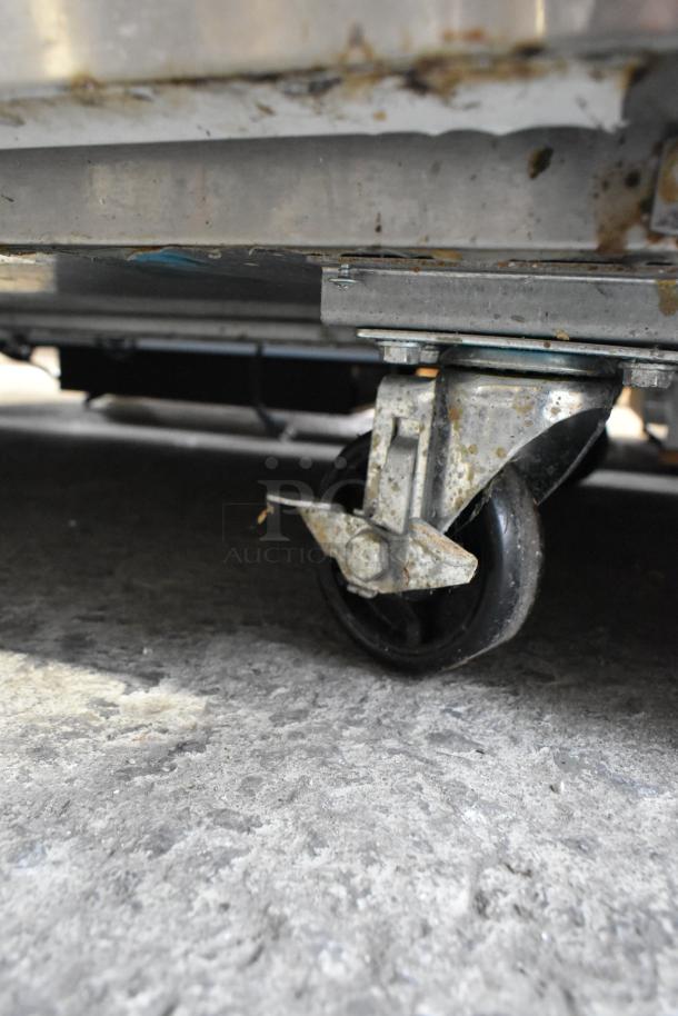 Close-up of a caster under a 2022 Avantco 178AU48FHC stainless steel commercial freezer, showing slight wear.
