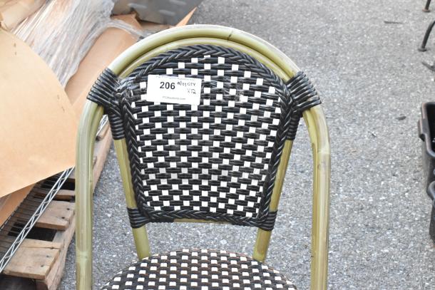 Outdoor wicker-style patio chair with woven black and white pattern. Slight wear visible. Tag indicates auction details.