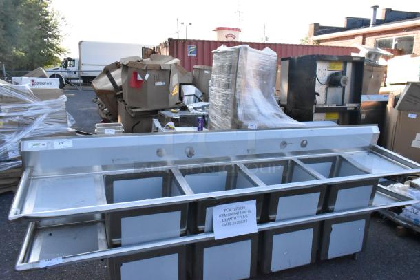 Brand new Regency 600S41818218 stainless steel four-compartment commercial sink with two drainboards, no legs, scratch and dent condition.