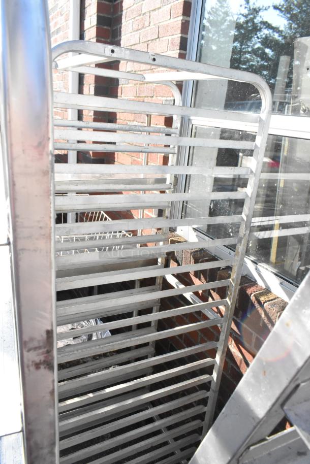 Two metal pan transport racks with multiple slots, mounted on commercial casters, suitable for kitchen use.