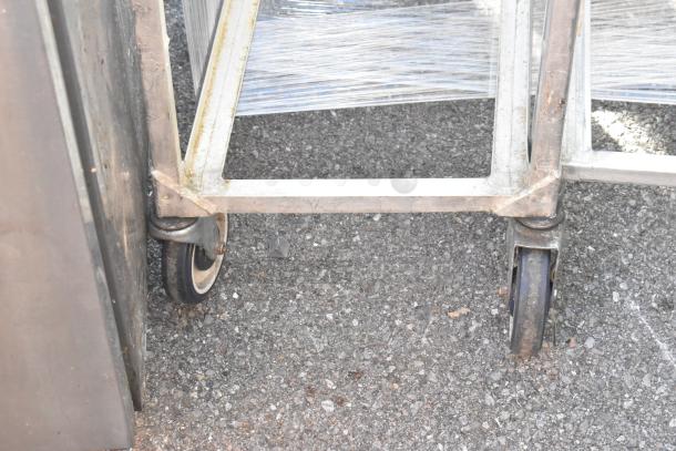 3 metal pan transport rack on commercial casters, shows minor wear, suitable for kitchen use, enhances storage mobility.
