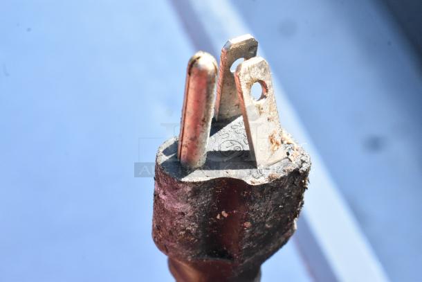 Close-up of a worn electrical plug with visible dirt and scratches, highlighting a three-prong design.