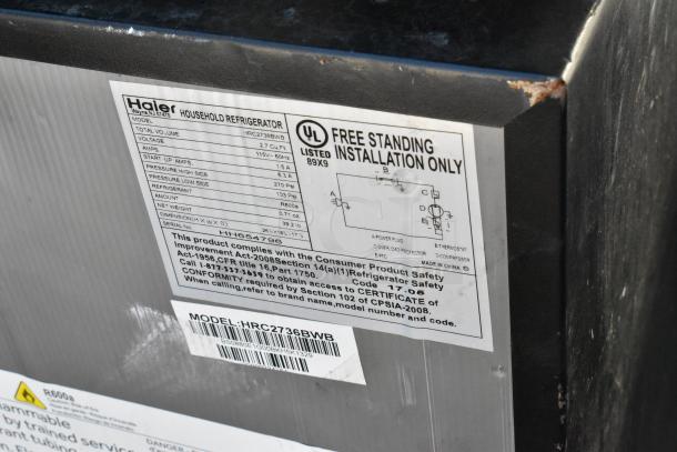Label on Haier HRC2736BWB refrigerator showing voltage, amps, refrigerant type, dimensions, and certification details.