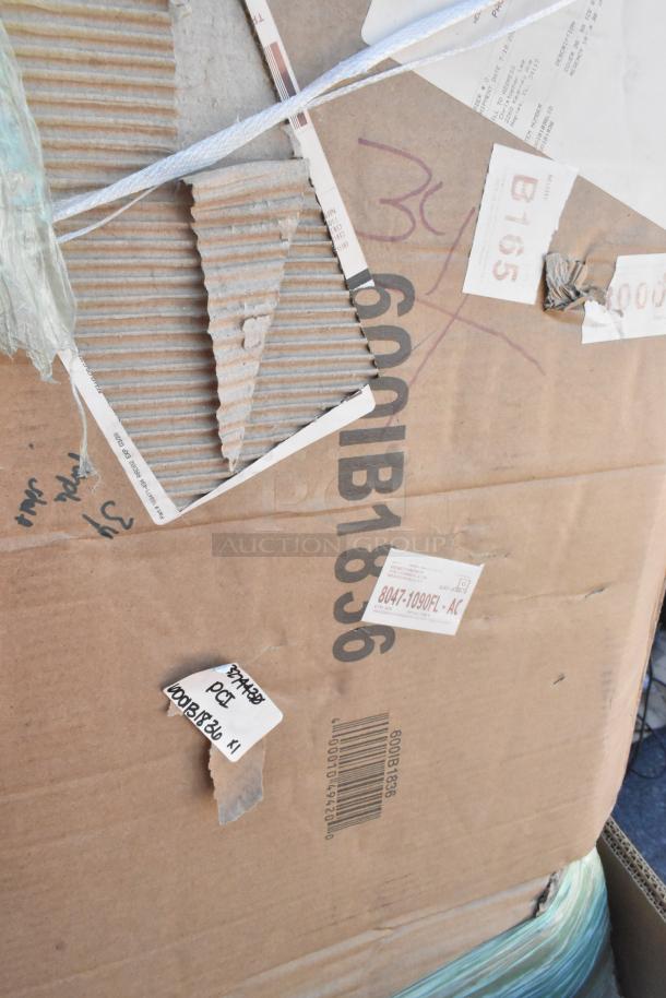 Cardboard box labeled "600IB1836" showing scratches and dents, containing Steelton and Regency stainless steel sinks and bins.