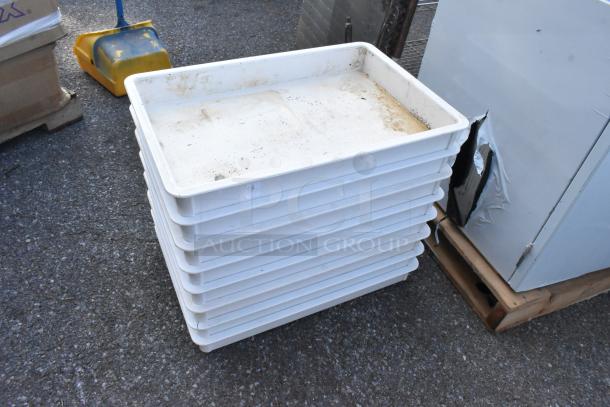 Eight poly bins, including seven stacked white dough bins and one clear bin, shown with wear and dirt marks on a paved surface.