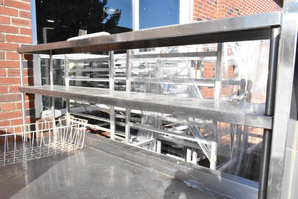 Stainless steel table with two-tier over shelf, under shelf, and mounted commercial can opener. Shows signs of use.