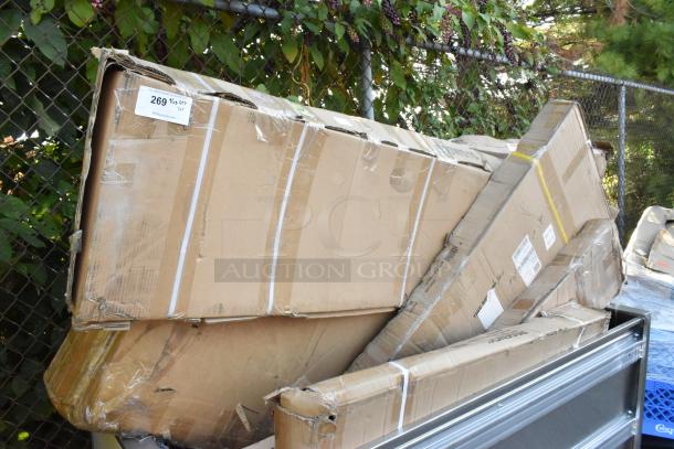 Boxes containing seven new scratch and dent Regency items, including stainless steel tables and shelves, labeled for auction sale.