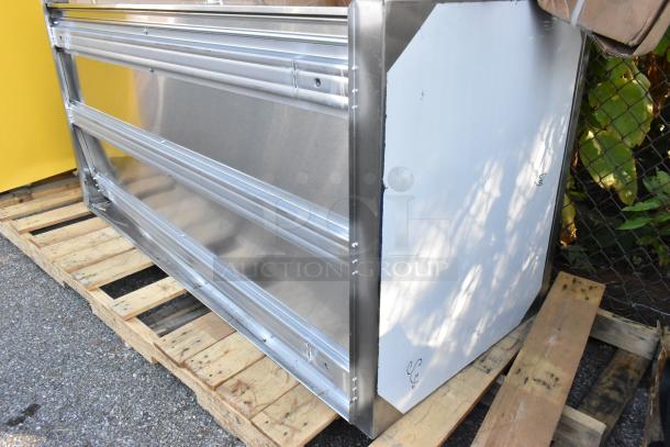 Brand new stainless steel counter, slight scratches and dents visible, resting on a wooden pallet outdoors.