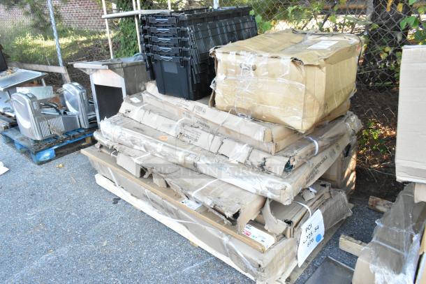 15 new scratch and dent items, including tables and wire shelves, in damaged packaging on pallets. Multicolor tape and labels visible.
