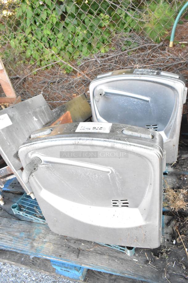 Two metal wall mount water fountains in used condition, on pallets. Labels show lot number 276.