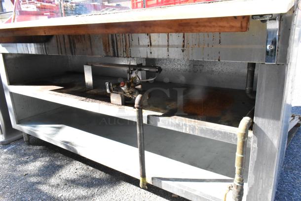 Stainless steel commercial steam table with sneeze guard and under shelf, visible wear, marked with gas hookup components.