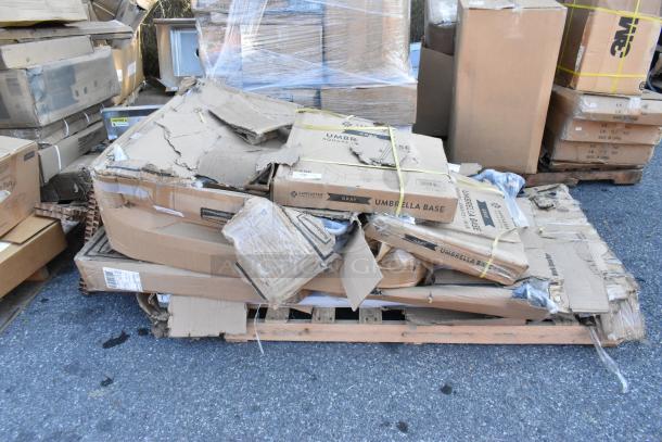 Six brand new boxed items, including Lancaster gray umbrella bases and work tables, on a wooden pallet. Boxes appear intact.