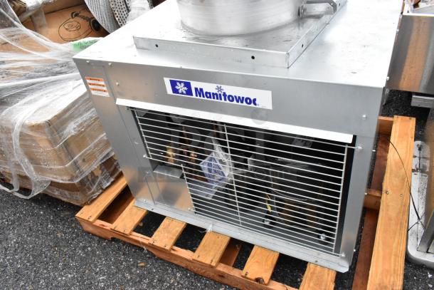 Brand new Manitowoc remote compressor for ice head, scratch and dent, metal casing on a pallet, labeled for identification.