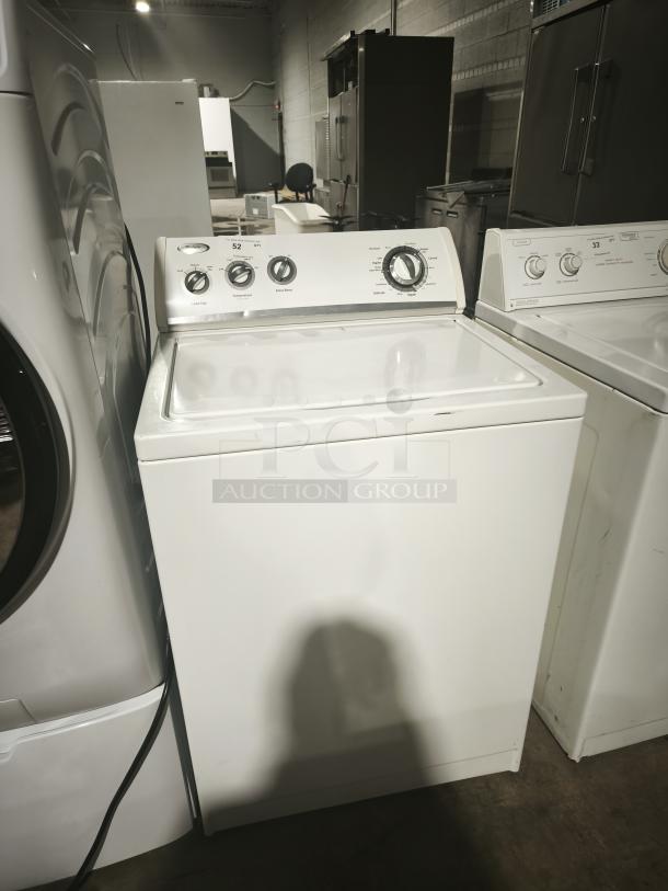 Whirlpool WTW5200VQ0 top-load washer, white, with control knobs, in good used condition, in warehouse setting.