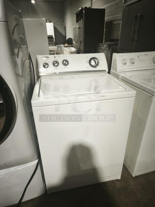 Whirlpool WTW5200VQ0 top-load washer, white, with control knobs, in good used condition, in warehouse setting.