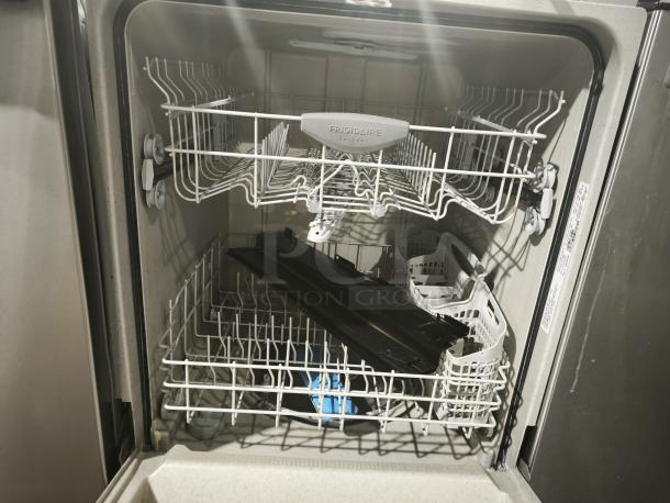 Frigidaire Gallery FGBD2445NF dishwasher, stainless interior, visible racks and utensil holder, model label on door edge.