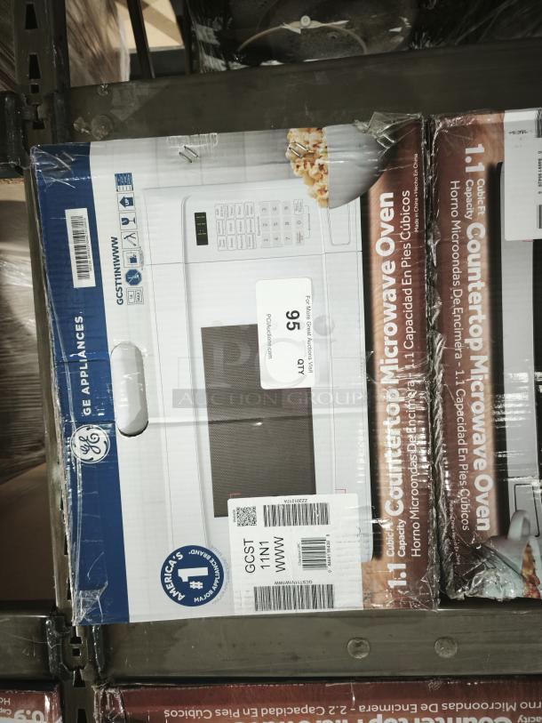 GE® 1.1 cu. ft. White Countertop Microwave Oven (Model GCST11N1WWW) in box, new condition, with visible GE branding.