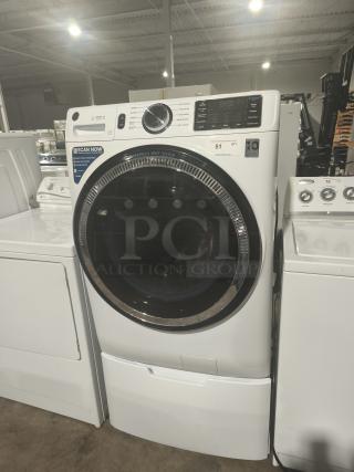 GE GFW550SSN2WW Smart Washer, white, front-load, control panel with dial and digital display, in showroom setting.