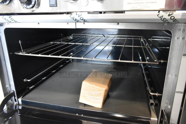 Brand new Southbend 4601DD 10-burner range oven, stainless steel, open oven showing racks, and control panel detail.