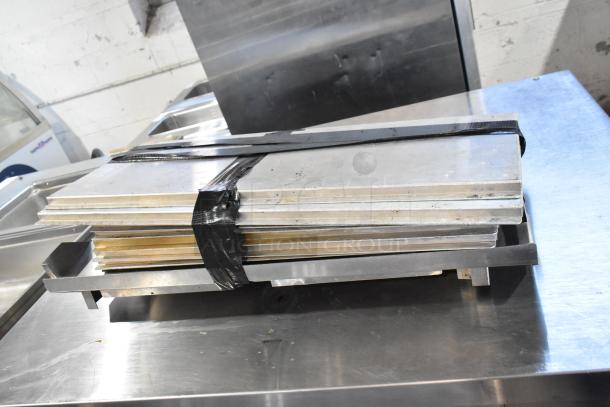 Stainless steel shelves strapped together, resting on a commercial-grade metal surface.