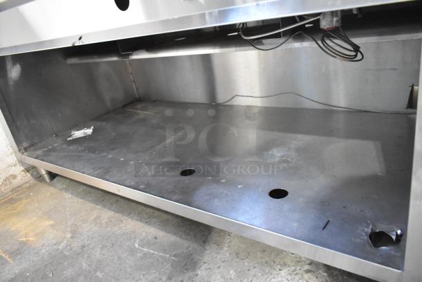 Stainless steel steam table with sneeze guard and under shelf. Features visible wiring, stainless finish, and shelf openings.