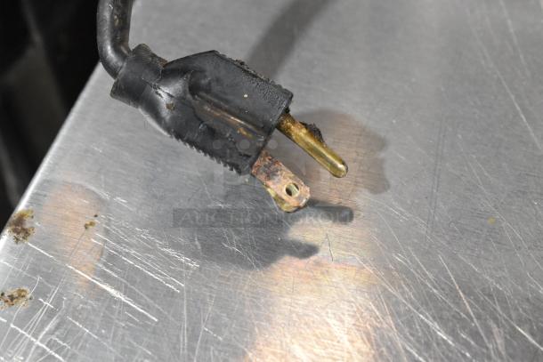 Delfield stainless steel prep table power plug with visible wear and tarnish on metallic prongs.