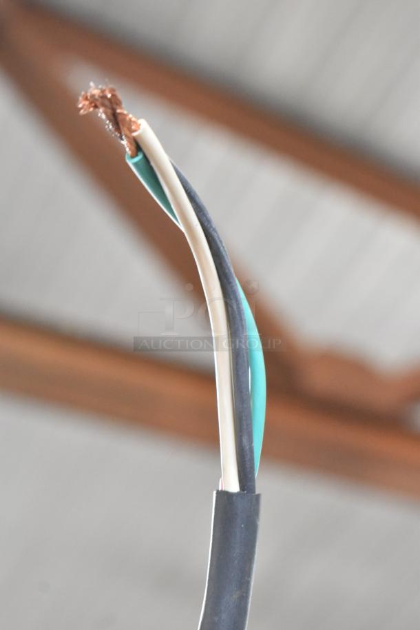 A close-up of frayed electrical wires with exposed copper, set against a blurred industrial background.