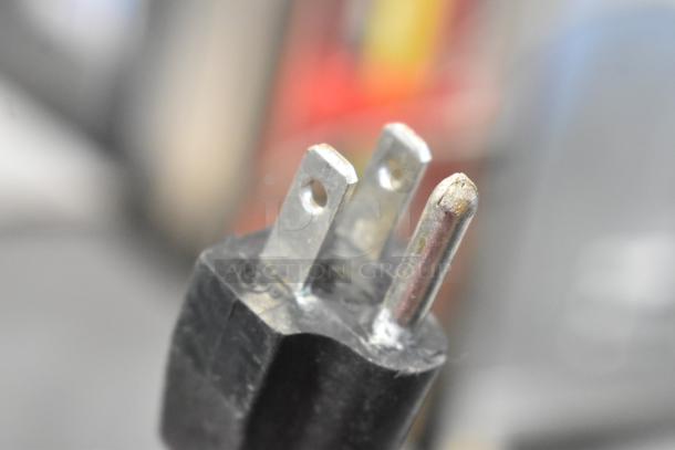 Close-up of a three-pronged electrical plug for L&J NY JUC-60 cooler, showing metal prongs and black casing.