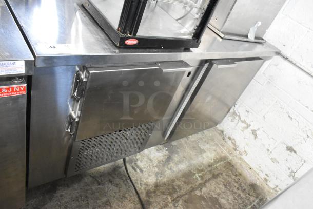 Stainless steel commercial 2-door undercounter cooler on casters, 115 volts, 1 phase, in used condition. Visible brand labels.