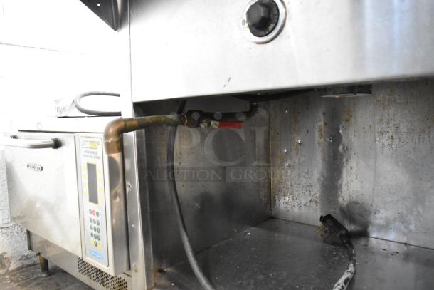 Stainless steel commercial steam table with sneeze guard, showing electric connections and control panel, moderate wear.