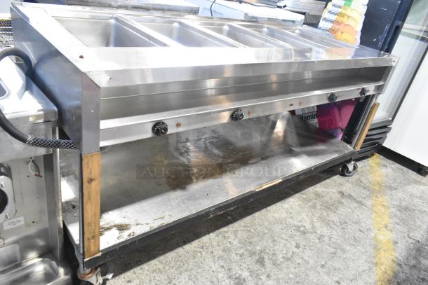 Stainless steel 4-bay steam table with under shelf, commercial casters, adjustable knobs, signs of wear.