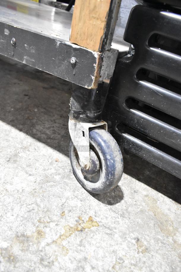 Stainless steel commercial 4 bay steam table caster, showing metal frame and wheel on a concrete floor.