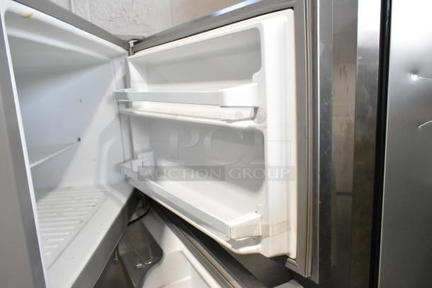 2020 Whirlpool WRT311FZDM01 stainless steel cooler with freezer, open door view, showing interior shelving. Appears in used condition.