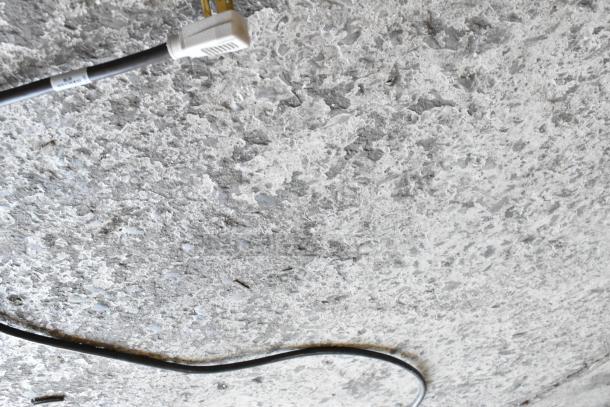 A close-up of a plug and cord on a speckled concrete surface.