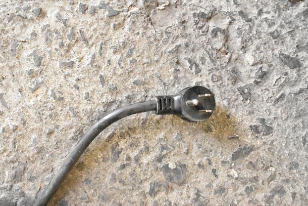 Power cord for IDW G-12-F334B-HC commercial cooler, standard 3-prong plug, on textured concrete surface.