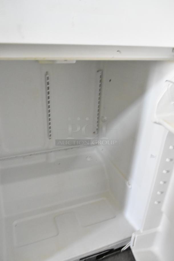 Whirlpool W1TXNMFWQ00 metal cooler with freezer, 115 volts, 1 phase. Interior view, clean condition, visible shelving slots.