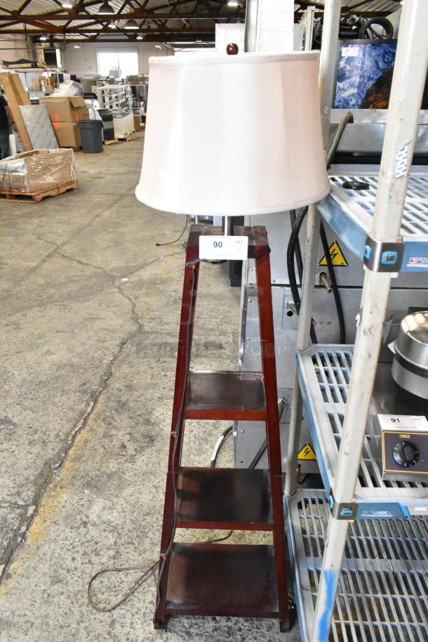 Tall wooden lamp with cream shade and three-tiered shelves, item number 90, in used condition.
