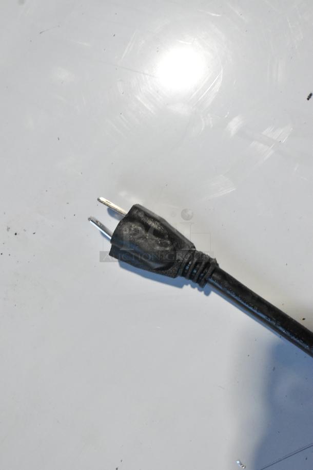 Close-up of a black electrical plug for the 2025 Scotsman 194MCH422A Stainless Steel Ice Machine, showing metal prongs.