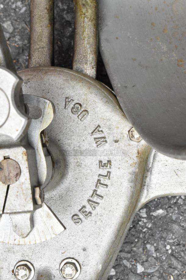 Belshaw metal commercial dough dropper with hopper and arm, marked "Seattle WA USA," showing signs of wear.