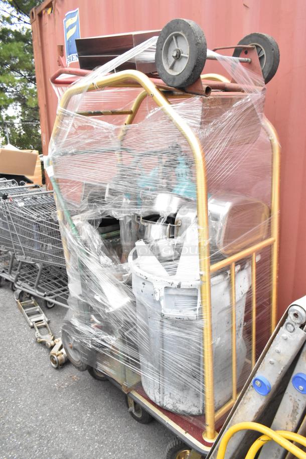 Metal luggage cart on commercial casters with metal baking pans and poly trash can, wrapped in plastic film.