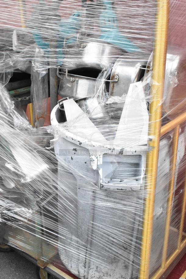 Metal luggage cart with commercial casters containing metal baking pans and a poly trash can, wrapped in plastic.