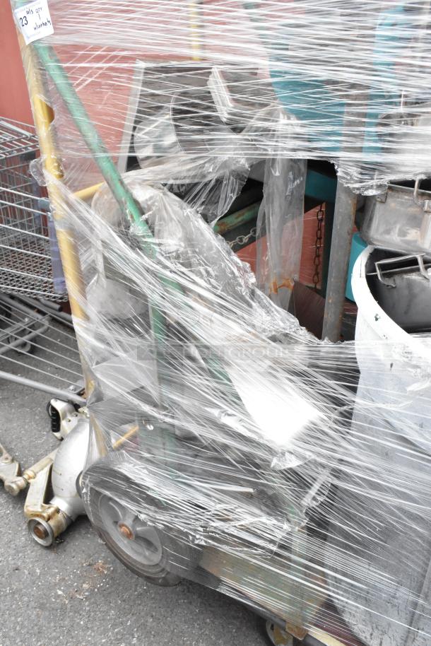 Metal luggage cart with commercial casters, holding metal baking pans and poly trash can, wrapped in plastic for protection.