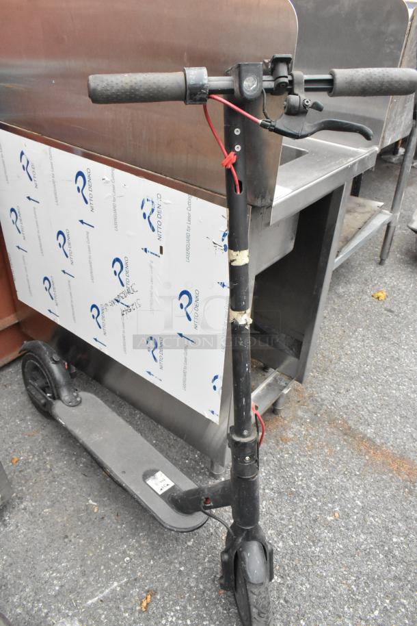 Two black scooters, one viewed up close, showing wear, with visible handlebars and front wheel.