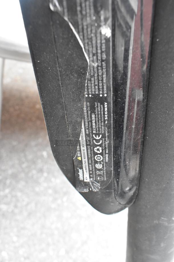 Close-up of Ninebot by Segway scooter label with model info, safety warnings, and specifications. Slight wear visible.