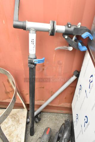 Clamp with stand in good condition, featuring a black and silver metal design. Label marked "127." Suitable for securing items.