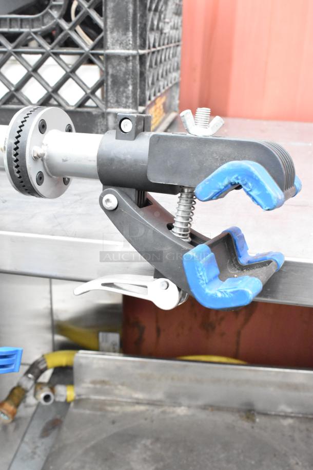 Adjustable clamp with stand, featuring blue rubber grips and metal spring mechanism, in good condition. Ideal for secure holds.