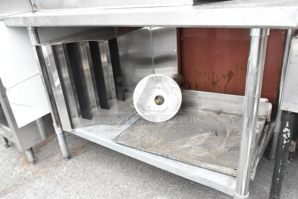 Stainless steel table with metal under shelf, featuring multiple slots and a triangular metal piece. Used condition.