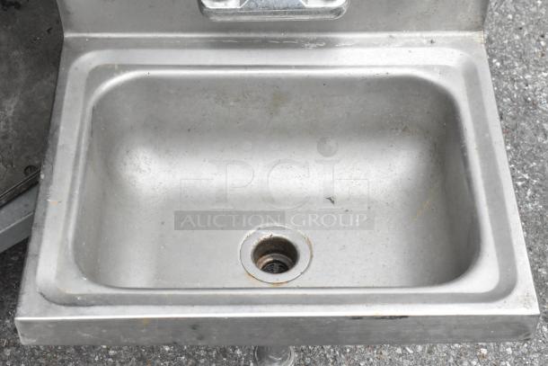 Stainless steel single bay sink with faucet and handles, shows signs of wear and surface stains.