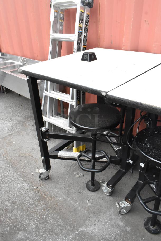 Three tables with attached stools, sizes 30x36x46, 51x36x46. Black frames, wheeled base, power outlets on tables.