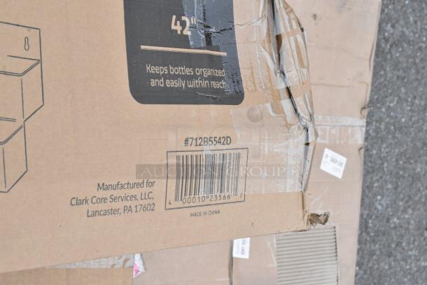 Cardboard packaging with "#712B5542D" and barcode, showing damage. Text reads "Keeps bottles organized" and "Manufactured for Clark Core Services, LLC, Lancaster, PA 17602, Made in China."